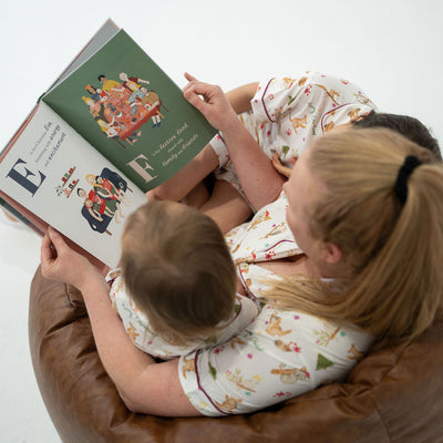 Woman and child sitting on a brown chair reading a book together.